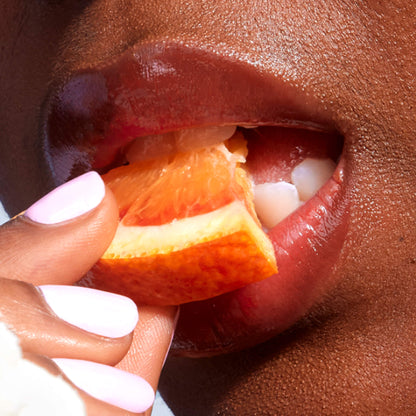 [A close up of a model wearing Tower 28 Beauty's LipSoftie™ Lip Treatment in Blood Orange Vanilla on her lips]