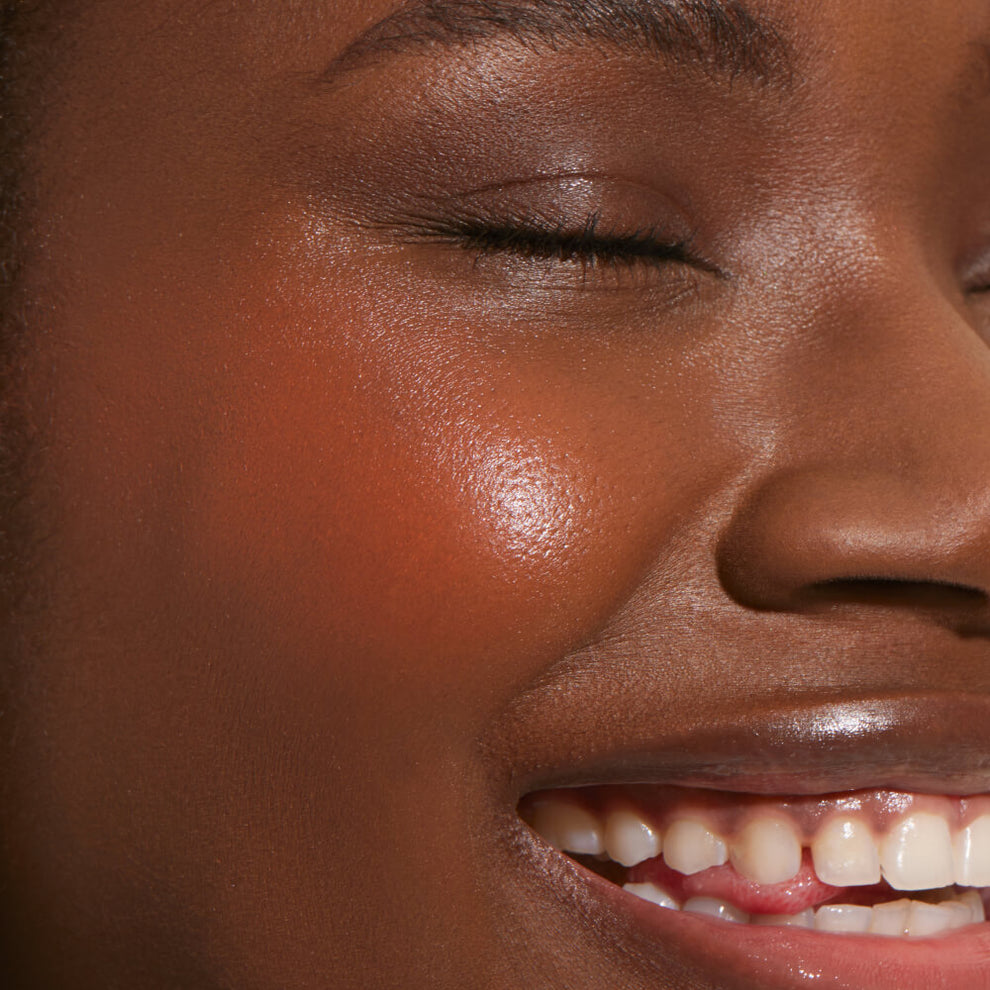 A close up of a model with Tower 28 Beauty's BeachPlease Cream Blush in Golden Hour on her face.