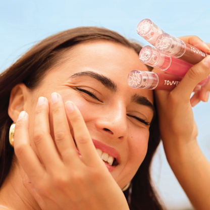 Milky Lip Set [Shared: Closeup photo of a girl with brown hair smiling, holding up 4 ShineOn Milky Lip Jellies (assorted shades) to her face]