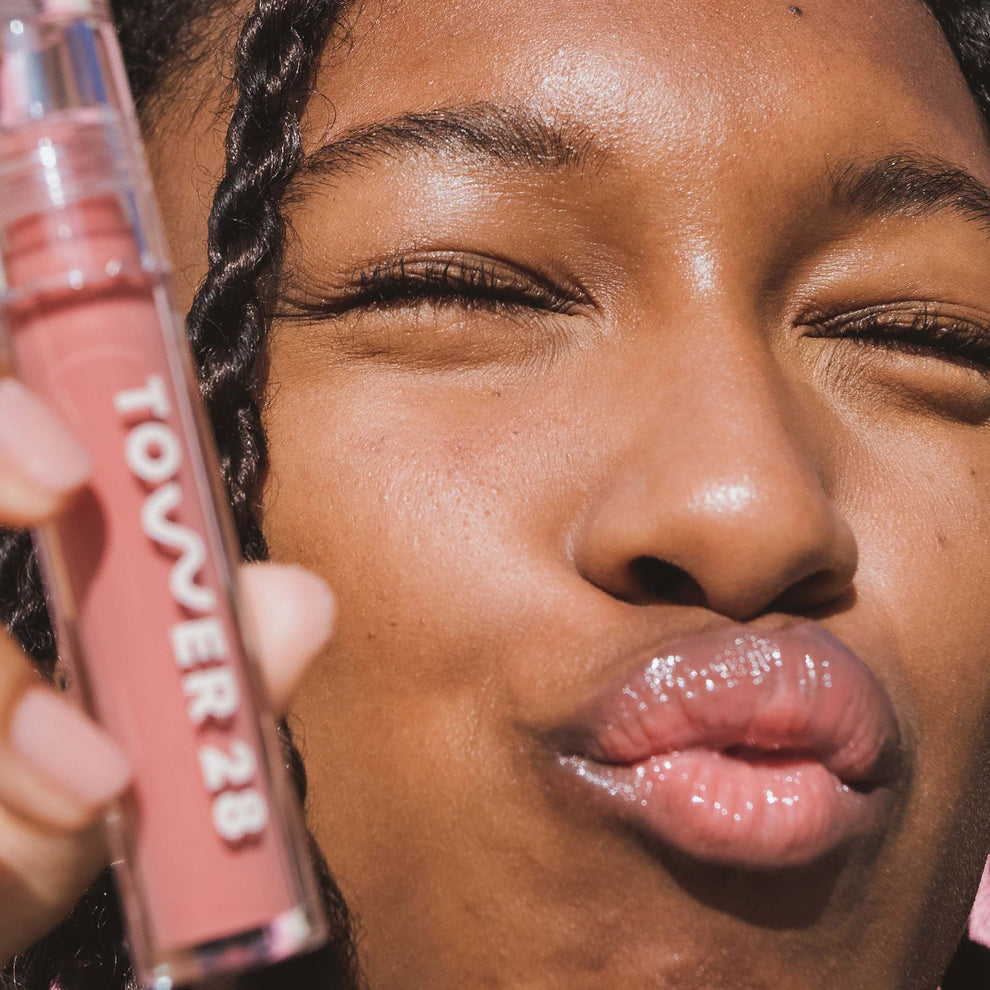 [Shared: Closeup photo of very glossy lips, smiling and wearing the Tower 28 Beauty ShineOn Milky Lip Jelly shade in Oat (a milky peachy-pink)